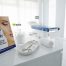 A copy of the book 'Your Guide to Modern Plastic Surgery' by Dr Laith Barnouti displayed on a white medical counter, accompanied by a sterile instrument tray, a glass jar of cotton, and a rolled towel in a bright, modern clinic setting.